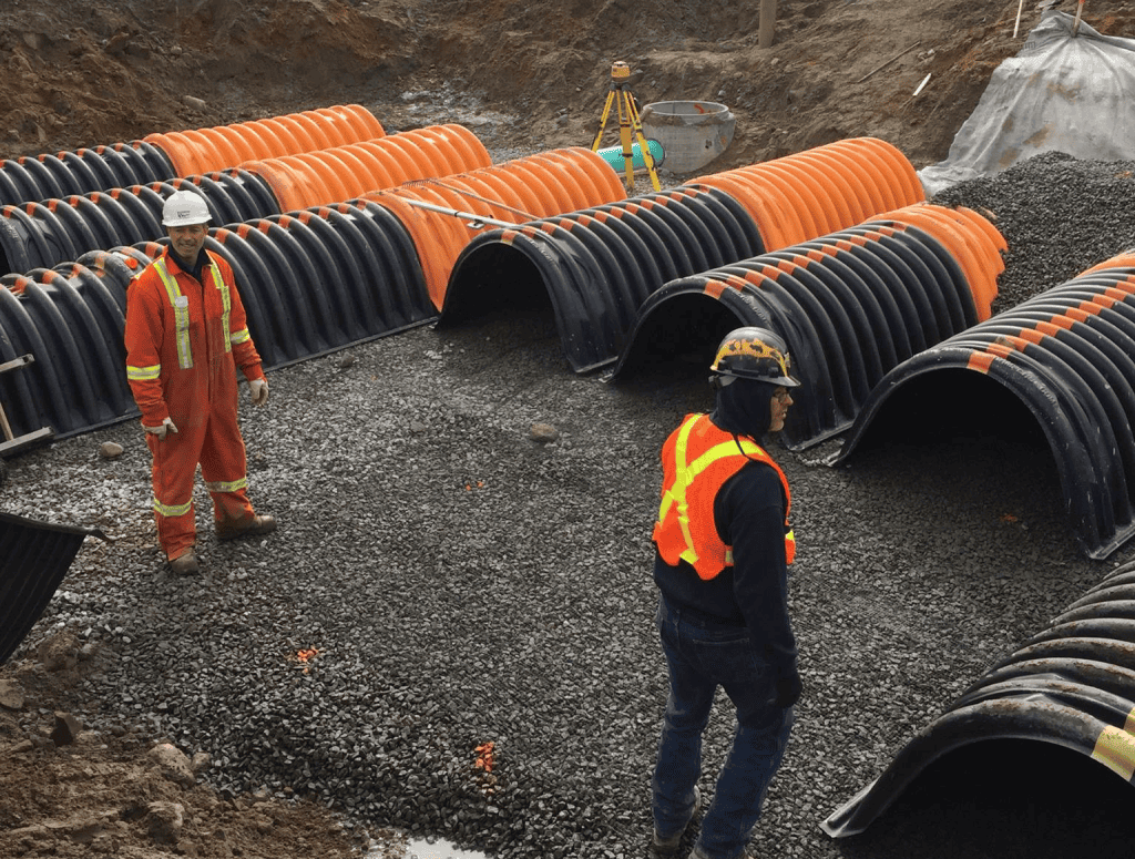Travailleurs en sécurité installant des conduits en plastique noir et orange.